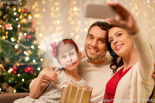 Image of happy family with christmas present at home