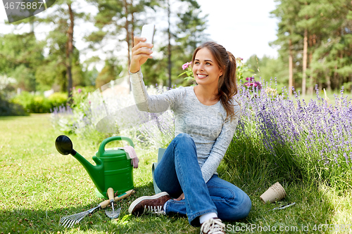 Image of woman taking selfie by smartphone in summer garden