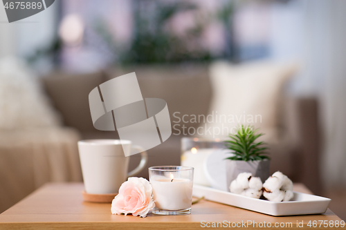 Image of burning candle and flower bunch on wooden table