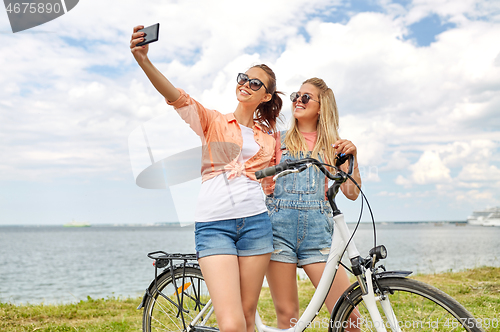 Image of teenage girls with bicycle taking selfie in summer