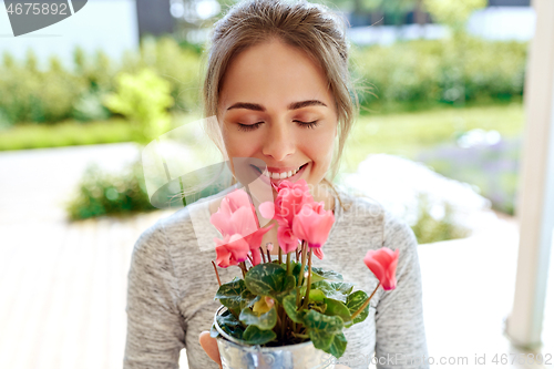 Image of young woman with cyclamen flowers at summer garden