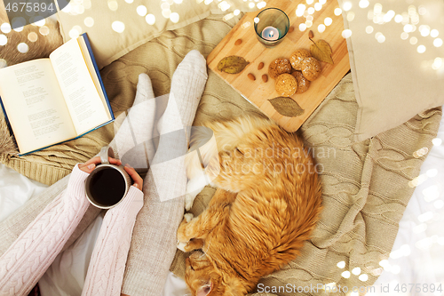 Image of woman with coffee and red cat sleeping in bed