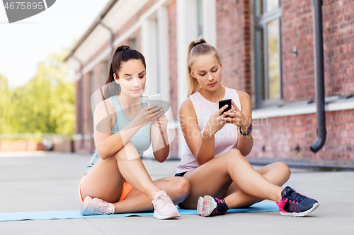 Image of sporty women or friends with smartphone on rooftop