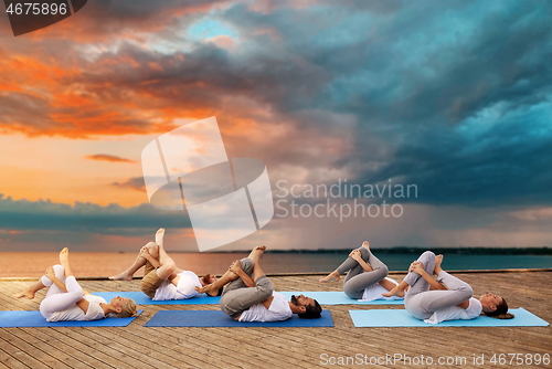 Image of group of people making yoga exercises outdoors