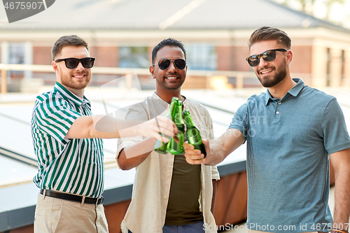 Image of happy male friends drinking beer at rooftop party