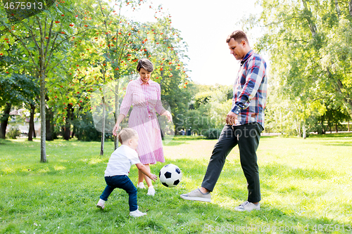 Image of happy family playing soccer at summer park