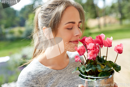 Image of young woman with cyclamen flowers at summer garden