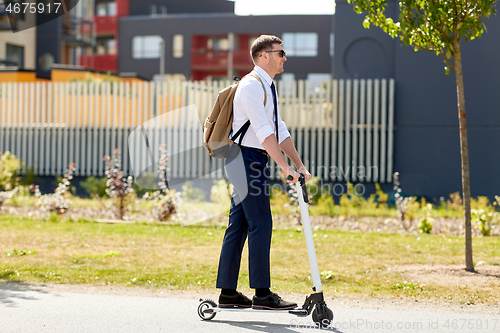 Image of businessman with backpack riding electric scooter