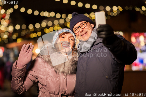 Image of senior couple taking selfie at christmas market