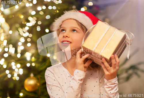 Image of smiling girl in santa hat with christmas gift