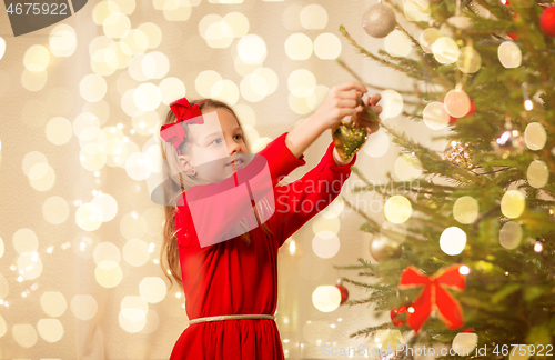 Image of happy girl in red dress decorating christmas tree