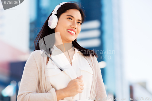 Image of happy smiling asian woman with headphones in city