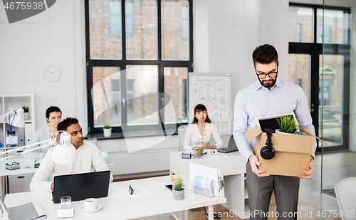 Image of sad fired male office worker with personal stuff