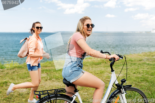 Image of teenage girls or friends with bicycle in summer