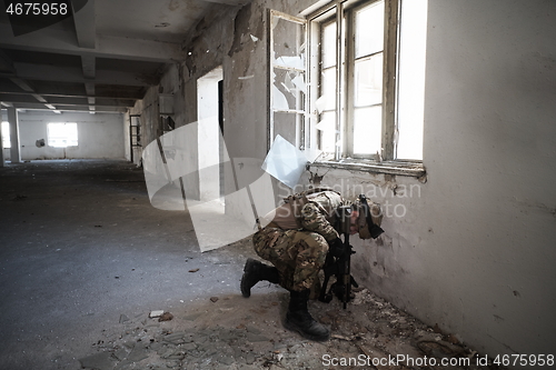 Image of soldier in action near window changing magazine and take cover