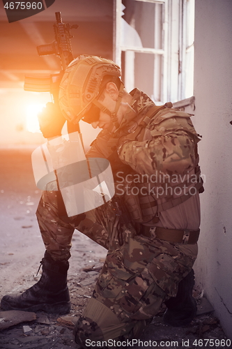 Image of soldier in action near window changing magazine and take cover