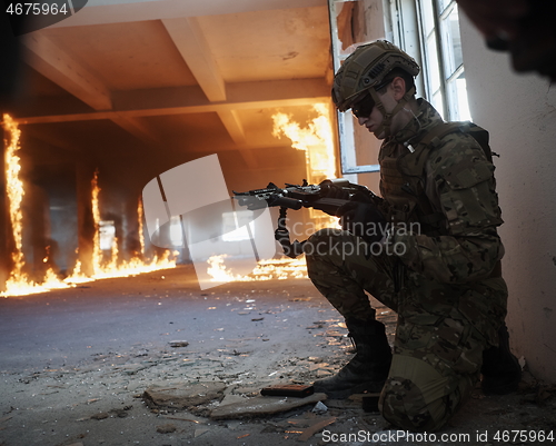 Image of soldier in action near window changing magazine and take cover