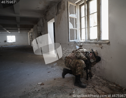 Image of soldier in action near window changing magazine and take cover