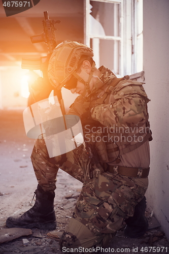 Image of soldier in action near window changing magazine and take cover