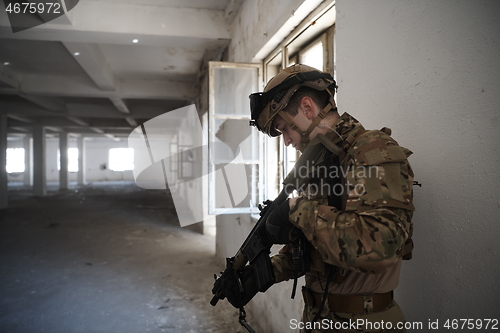 Image of soldier in action near window changing magazine and take cover