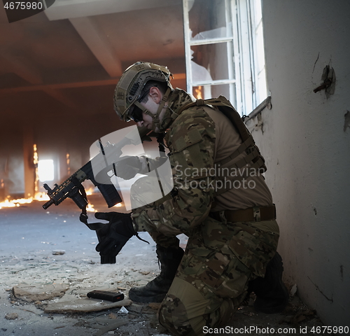 Image of soldier in action near window changing magazine and take cover