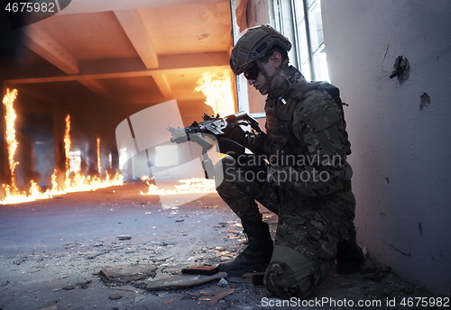 Image of soldier in action near window changing magazine and take cover