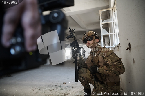 Image of soldier in action near window changing magazine and take cover