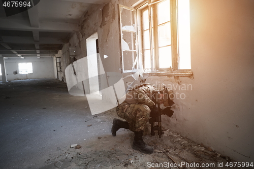 Image of soldier in action near window changing magazine and take cover