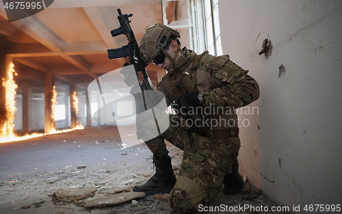 Image of soldier in action near window changing magazine and take cover