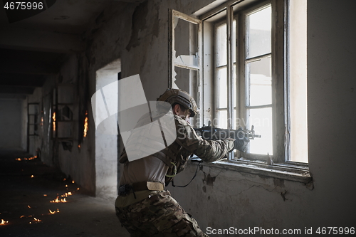 Image of soldier in action near window changing magazine and take cover