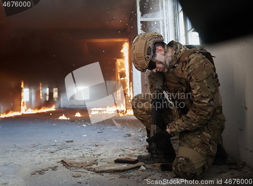 Image of soldier in action near window changing magazine and take cover