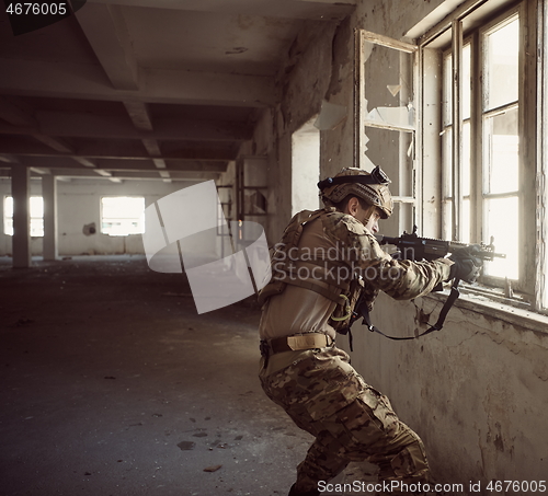 Image of soldier in action near window changing magazine and take cover