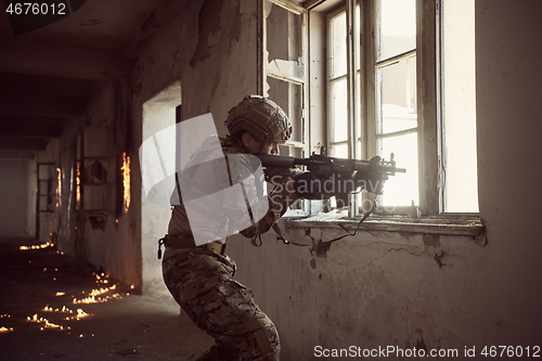 Image of soldier in action near window changing magazine and take cover