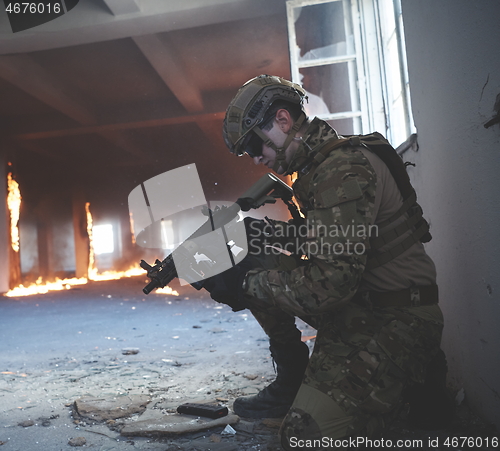 Image of soldier in action near window changing magazine and take cover