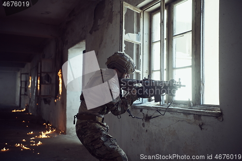 Image of soldier in action near window changing magazine and take cover