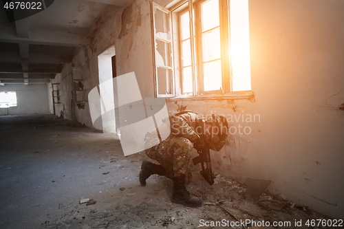 Image of soldier in action near window changing magazine and take cover