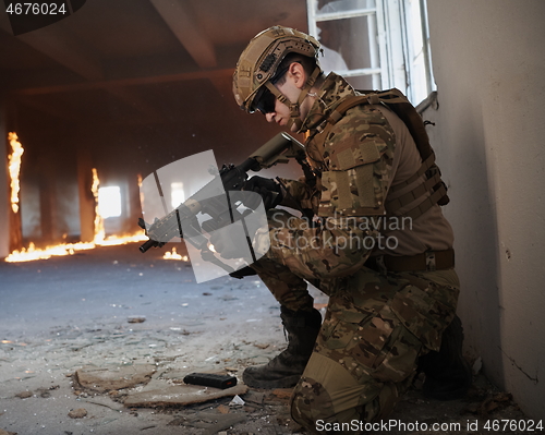 Image of soldier in action near window changing magazine and take cover