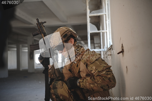 Image of soldier in action near window changing magazine and take cover