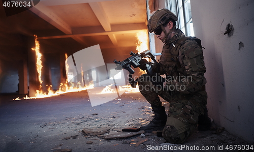 Image of soldier in action near window changing magazine and take cover