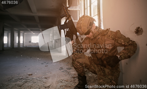 Image of soldier in action near window changing magazine and take cover