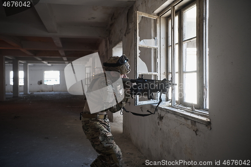 Image of soldier in action near window changing magazine and take cover