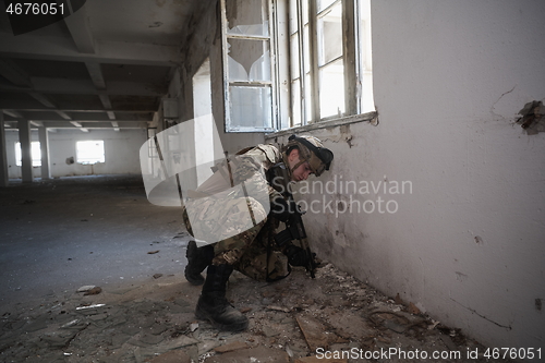 Image of soldier in action near window changing magazine and take cover