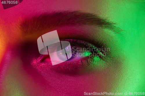 Image of Close up portrait of female fashion model in neon light on dark studio background.