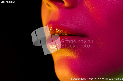 Image of Close up portrait of female fashion model in neon light on dark studio background.