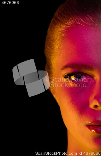 Image of Portrait of female fashion model in neon light on dark studio background.