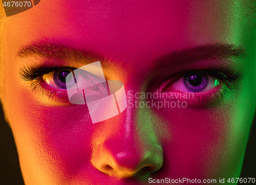 Image of Close up portrait of female fashion model in neon light on dark studio background.