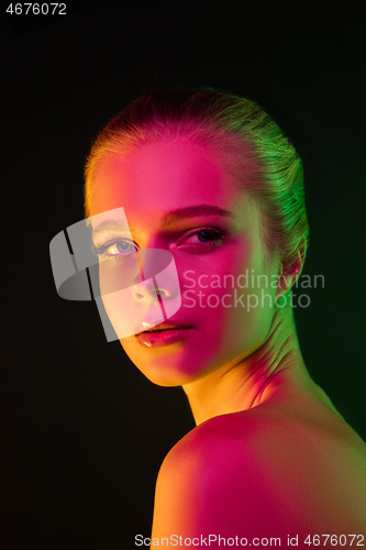 Image of Portrait of female fashion model in neon light on dark studio background.