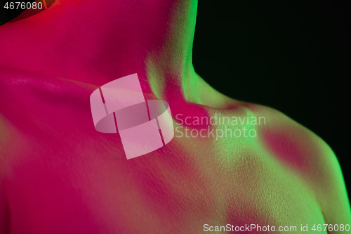 Image of Close up portrait of female fashion model in neon light on dark studio background.