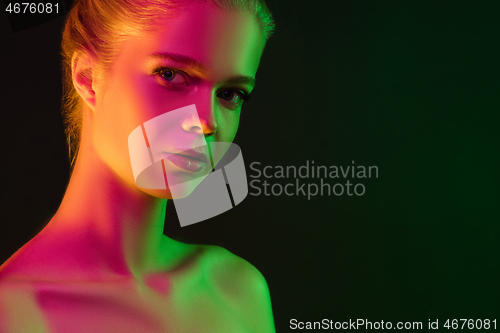 Image of Portrait of female fashion model in neon light on dark studio background.