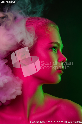 Image of Portrait of female fashion model in neon light on dark studio background.